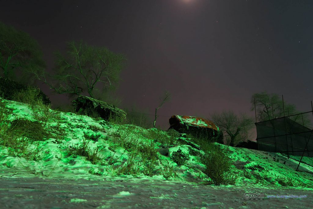 韩屯村松花江畔，积雪由于对岸的灯光显出了绿色，天空中星星偶尔可见